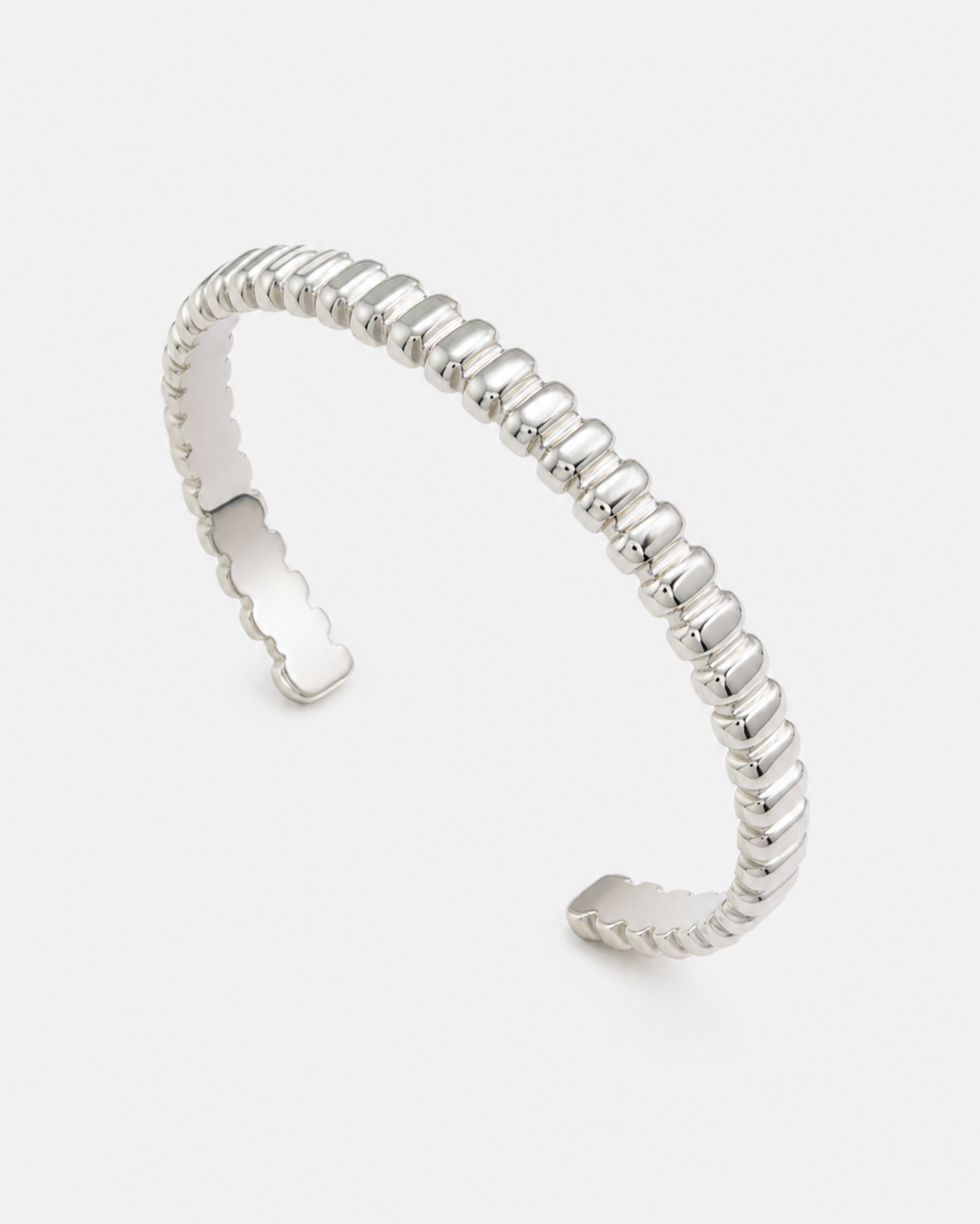 Offener silberfarbener Edelstahl-Cuff Armreif mit geriffelter, moderner Struktur auf hellem Hintergrund.