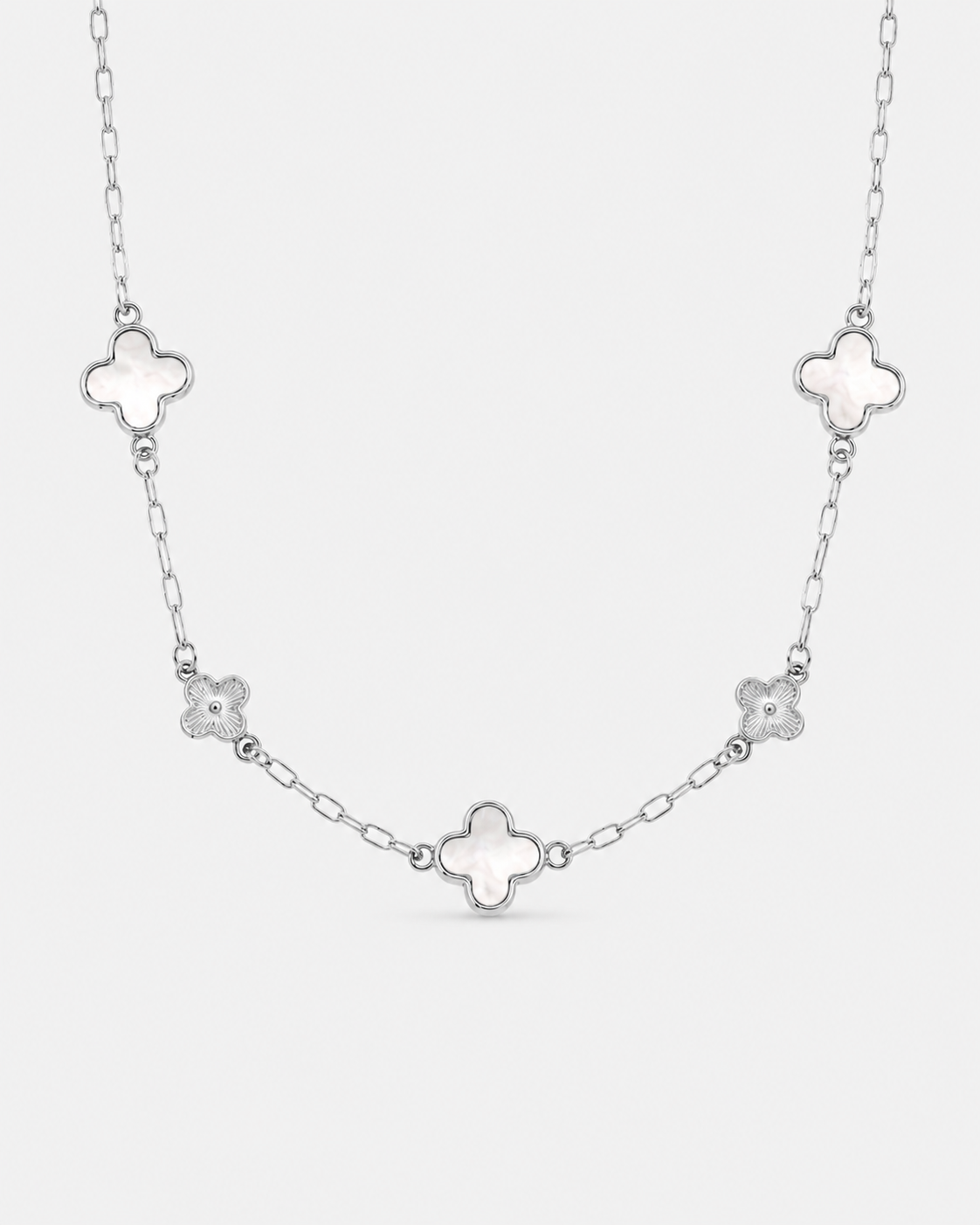 Silberfarbene Halskette aus Edelstahl mit drei Kleeblatt-Anhängern in Perlmutt-Optik und zwei filigranen Blumen-Elementen an einer feinen Gliederkette.