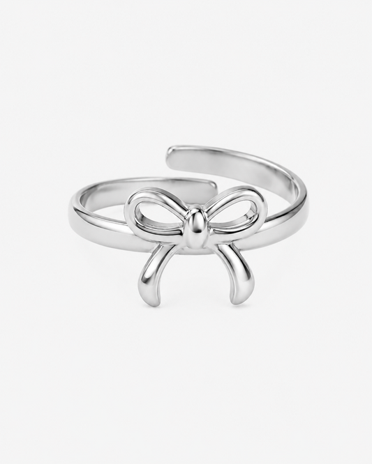 Silberfarbener, verstellbarer Ring aus Edelstahl mit filigranem Schleifen-Design. Der Ring besitzt eine glänzende Oberfläche und eine elegante Ausstrahlung.