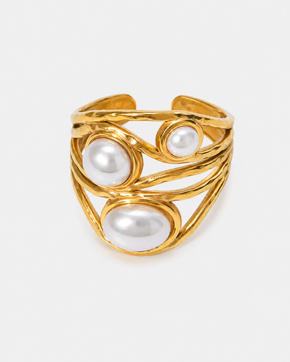 Goldfarbener Chunky Statement Ring aus Edelstahl mit 18 Karat Vergoldung, organischem mehrlagigem Design und drei weißen Perlen auf hellem neutralem Hintergrund.
