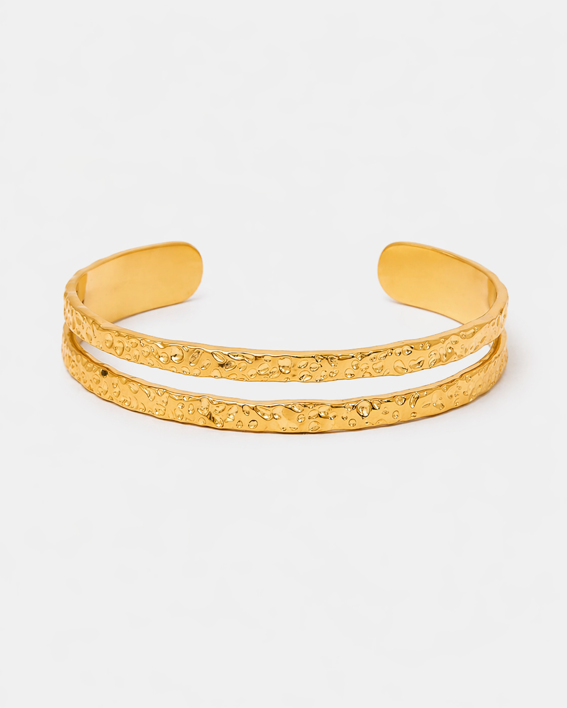 Goldfarbener offener Armreif aus Edelstahl mit 18 Karat Vergoldung, doppeltem gehämmertem Design und strukturierter Oberfläche auf hellem neutralem Hintergrund.