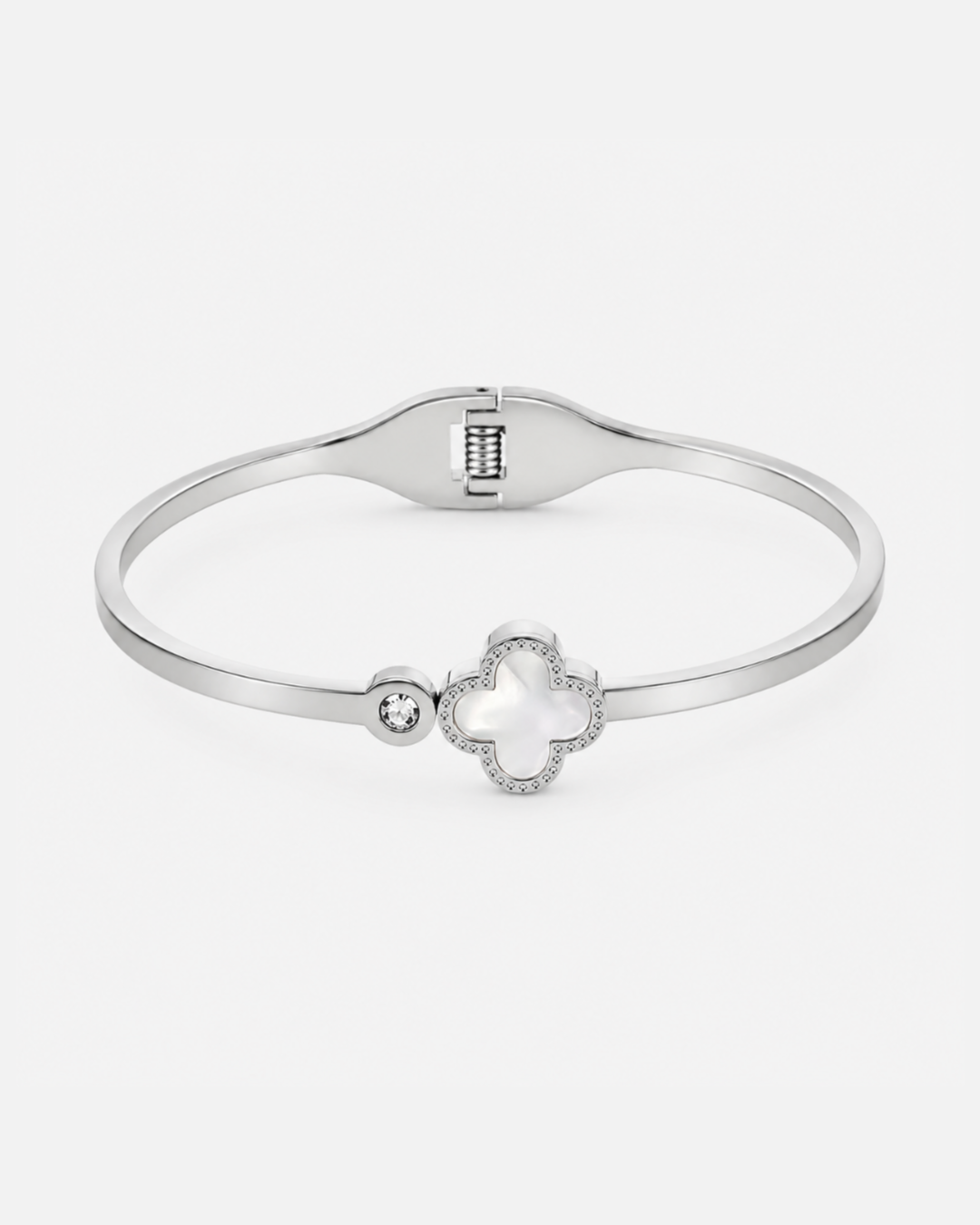 Silberfarbener Edelstahl-Armreif mit elegantem Kleeblatt-Motiv, Perlmutt-Detail und funkelndem Zirkonia-Stein auf hellem Hintergrund.