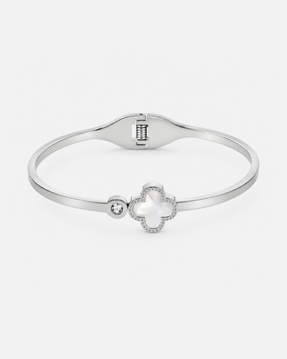 Silberfarbener Edelstahl-Armreif mit elegantem Kleeblatt-Motiv, Perlmutt-Detail und funkelndem Zirkonia-Stein auf hellem Hintergrund.