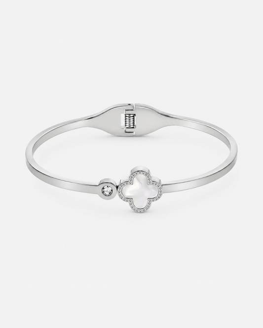 Silberfarbener Edelstahl-Armreif mit elegantem Kleeblatt-Motiv, Perlmutt-Detail und funkelndem Zirkonia-Stein auf hellem Hintergrund.
