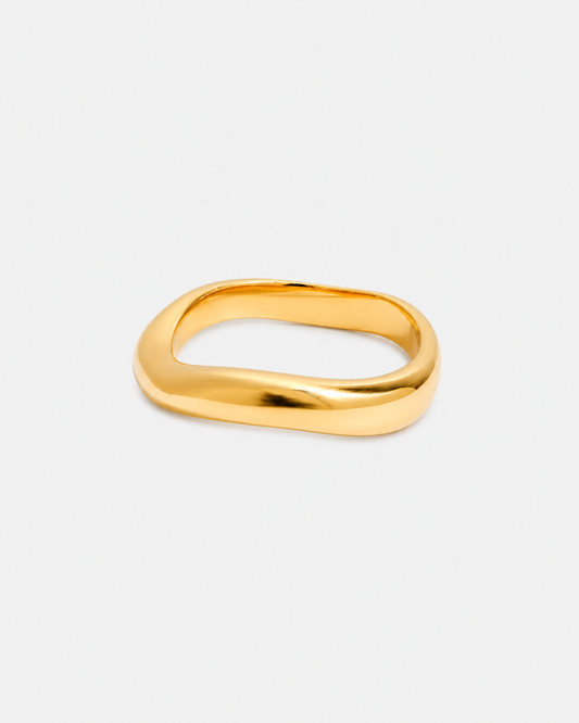 Vergoldeter Edelstahl-Ring mit weicher, organischer Silhouette und glänzender Oberfläche auf hellem Hintergrund.