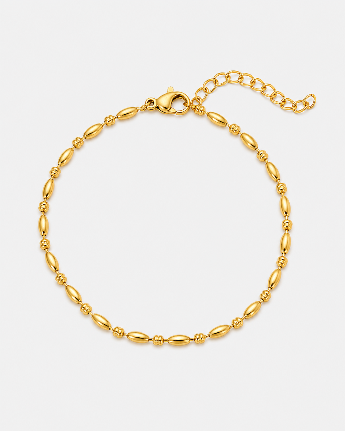 Feines vergoldetes Edelstahl-Armband mit ovalen Elementen, zarten Details und Verlängerungskette auf hellem Hintergrund.