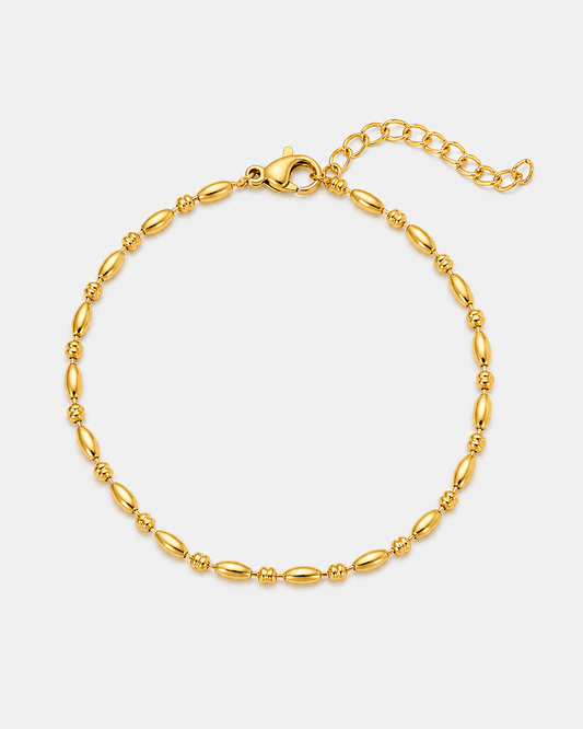 Feines vergoldetes Edelstahl-Armband mit ovalen Elementen, zarten Details und Verlängerungskette auf hellem Hintergrund.